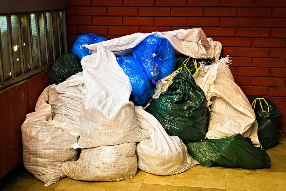 Купчина пълни чували и торби, оставени до тухлена стена