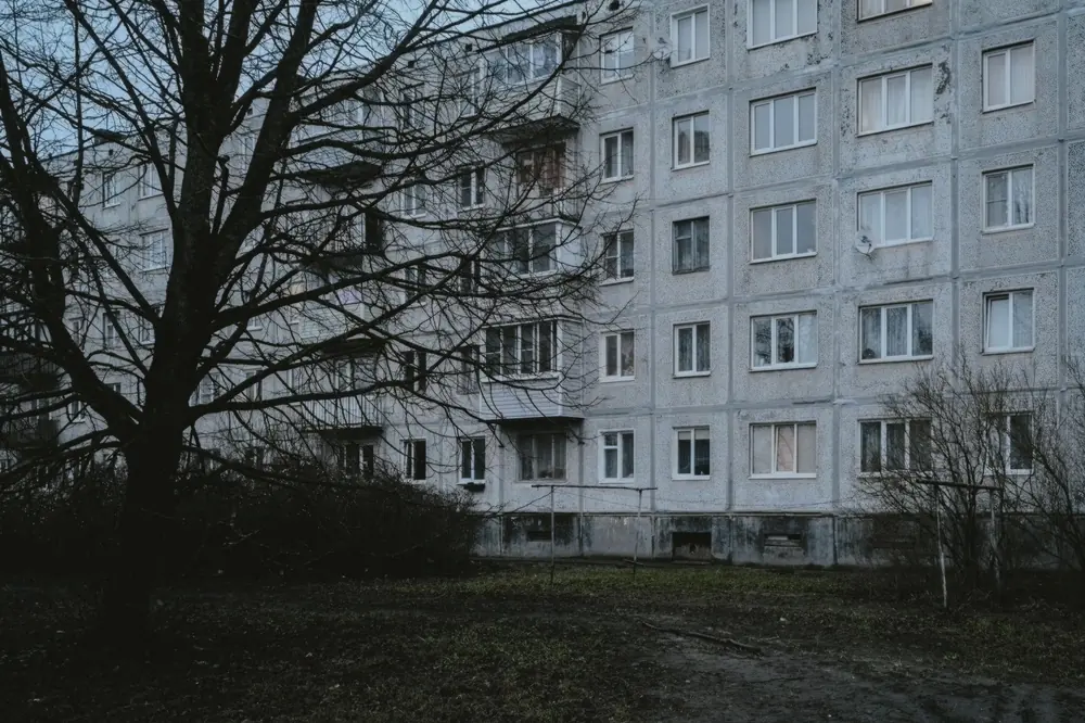 Сив панелен блок, пред него голо дърво