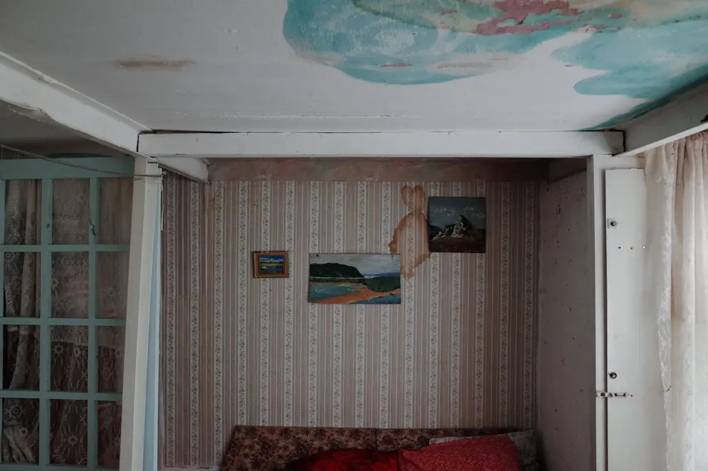 Стара стая с тапети на райета, кафеникаво петно от вода по тапета и петна по тавана над леглото