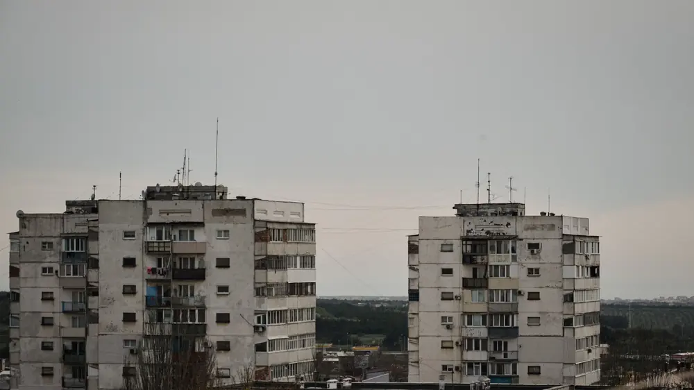 Два високи панелни жилищни блока с балкони и антени на покрива под сиво облачно небе